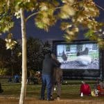 large inflatable movie screen at Buffalo Bayou Park in Houston with Yue Nakayama's video, Recycled Air, projected, three chickens are on the screen.